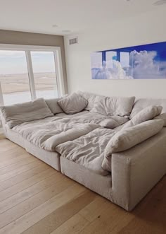 a large couch sitting in front of a window on top of a hard wood floor