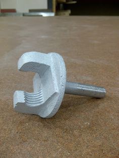 a close up of a metal object on the ground with a wrench in it