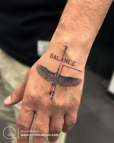 a man's hand with a tattoo on it that says balance and an arrow