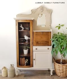 a white cabinet sitting next to a potted plant