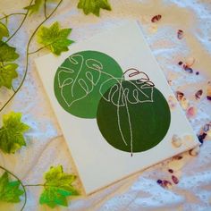 two cards with the word love written in cursive writing on them, surrounded by green leaves