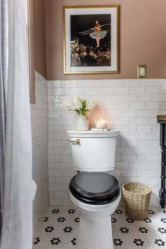 a white toilet sitting in a bathroom next to a painting on the wall above it