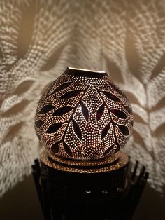 a decorative vase sitting on top of a black table next to a white and brown wall