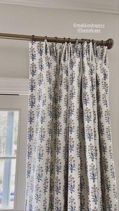 a curtain with blue and white flowers hanging from it's rodulage, in front of a window