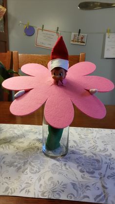 an elf's face is peeking out from behind a pink flower in a vase