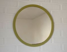 a round mirror mounted to the side of a white brick wall