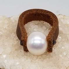 Elevate Your Style with Leather and Pearl Ring - A Captivating Fusion of Elegance and Artistry Step into a realm of unique elegance with our Leather and Pearl Ring, a masterpiece meticulously handcrafted by the artisans at PS121 Jewelry. This ring transcends mere adornment; it's a harmonious blend of natural beauty and artistic craftsmanship that resonates with your individuality and personal style. A Symphony of Elements: Adorn your finger with the exquisite interplay of leather and pearls, exp Formal Handmade Leather Jewelry, Elegant White Leather Jewelry, Leather Round Jewelry For Gifts, Handmade Pearl Open Ring For Formal Occasions, Luxury White Leather Jewelry, Unique Handmade Pearl Ring For Formal Occasions, Handmade White Leather Jewelry, Unique Handmade Pearl Rings, Pearl And Leather Jewelry