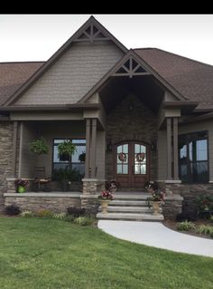 a house that is in the grass with flowers on the front porch and steps leading up to it