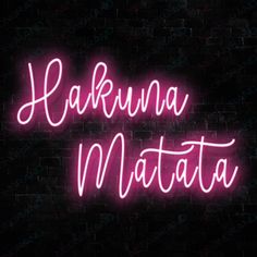 the neon sign that says kahuna matata in pink on a black brick wall