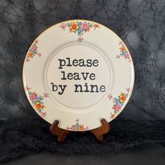 a plate that says please leave by nine on the front with flowers and leaves around it