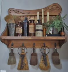 a shelf filled with bottles and brooms on top of a wooden shelf next to a potted plant