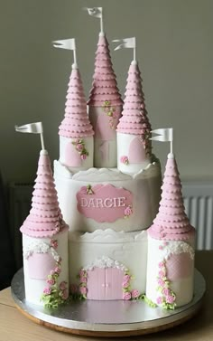 a cake that is shaped like a castle with pink turrets and flowers on the outside