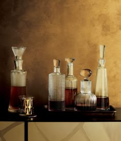 an assortment of vases on a table in front of a brown wall with gold paint