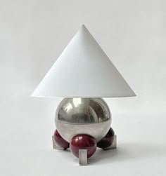 a silver object with a white triangle on it's head and two red balls in front of it