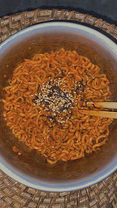 a bowl filled with noodles and chopsticks on top of a table