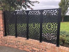 a brick wall with an intricate design on it and some trees in the background,