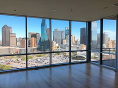 an empty room with large windows looking out at the cityscape and parking lot