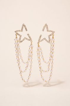 The Astra Pearl Draped Star Earrings are the perfect finishing touch to any outfit. The gold finish adds a touch of glamour, while the star design and pearl accents add a touch of sophistication. These earrings are designed with a hanging pearl, giving them a unique and eye-catching look. Whether you're dressing up for a special occasion or just looking to add some flair to your everyday look, these earrings are sure to impress. Plus, with their affordable price and trendy design, they make a gr Affordable Gold Trendy Pearl Earrings, Gold Pearl Earrings, Star Design, First They Came, Star Earrings, Star Designs, Gold Stars, Pearl Beads, Beautiful Earrings