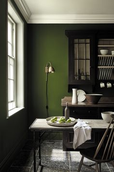 a dining room with green walls and black furniture