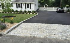 a driveway is paved with cobblestones and has a car parked in the driveway