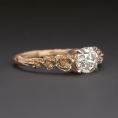 an antique engagement ring with three roses on the side and a round diamond in the center