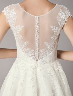 the back of a woman's wedding dress with white lace and flowers on it