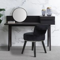 a black desk with a mirror and two vases on it next to a plant