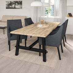 a wooden table with chairs around it in a living room next to a couch and coffee table