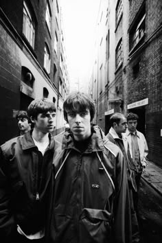 black and white photograph of young men walking down an alleyway in the city, looking at camera