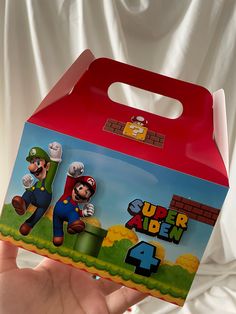 a hand holding up a red box with mario and luigi on it's side