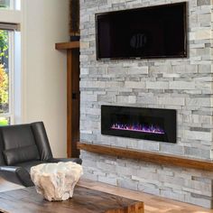 a living room with a large stone fireplace and flat screen tv mounted on the wall