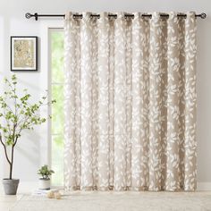 the curtains are hanging in front of a window with white flowers and leaves on it