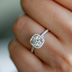 a close up of a person's hand holding a diamond ring