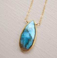 Labradorite encapsulates grace, mystery, and the timeless allure of natural beauty... Handcrafted with exquisite attention to detail, this Labradorite pendant showcases the gem's iridescent blues, greens, and grays, which flicker and change with the light. Labradorite, a feldspar originally found in Labrador Island, Canada, was believed to be fallen fire from the Aurora Borealis by the Inuit people. It is a protective gemstone, said to help support us through transformation and everyday life cha Handmade Drop-shaped Labradorite Necklaces, Handmade Labradorite Drop Necklaces, Teardrop Gemstone Jewelry For Meditation, Teardrop Labradorite Jewelry Gift, Labradorite Drop Jewelry For Gift, Handmade Labradorite Drop Necklace, Nature-inspired Teardrop Gemstone Jewelry, Teardrop Labradorite Jewelry With Large Stone, Labradorite Gemstone Teardrop Pendant Jewelry