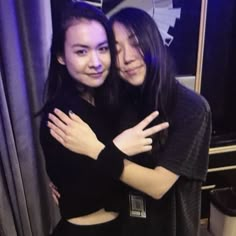 two young women hugging each other in front of a mirror with their arms around one another