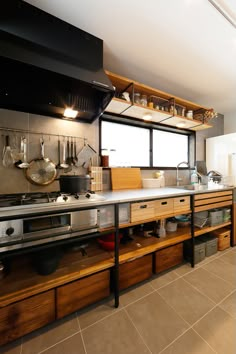 an industrial style kitchen with wooden cabinets and stainless steel counter tops, along with pots and pans hanging on the wall