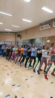 a group of people standing on top of a wooden floor next to each other in a gym