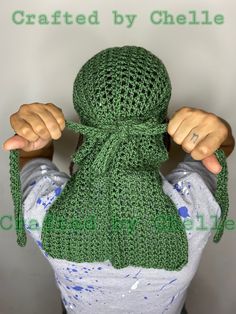 a person wearing a green knitted scarf with their hands on the back of his head