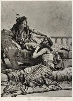 an old photo of two women sitting on a bed