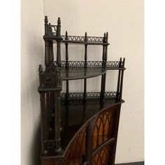 an old wooden shelf with ornate carvings on the top and bottom, in front of a white wall