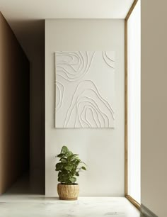 a potted plant sitting on top of a white counter next to a wall mounted art piece