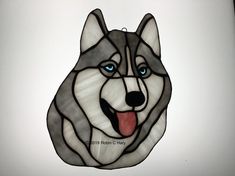 a stained glass husky dog with blue eyes and tongue hanging from the side of a wall