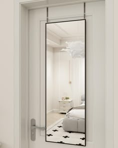 a mirror reflecting a bed in a white room with black and white rugs on the floor