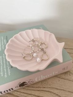 there is a pink shell with pearls in it on top of a book that reads ghost's