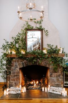 the fireplace is decorated with candles and greenery