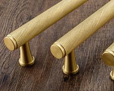 three brass colored handles on a wooden surface