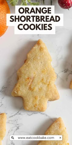 orange shortbread cookies are arranged on a marble surface with fresh fruit in the background