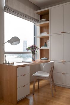 a white chair sitting in front of a wooden desk next to a window with a view