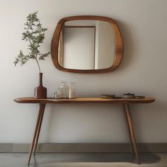 a wooden table topped with a mirror and vase