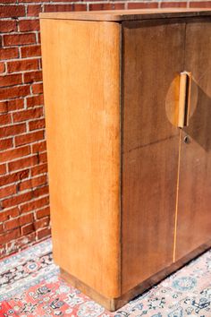 an old wooden cabinet sitting on top of a rug next to a red brick wall